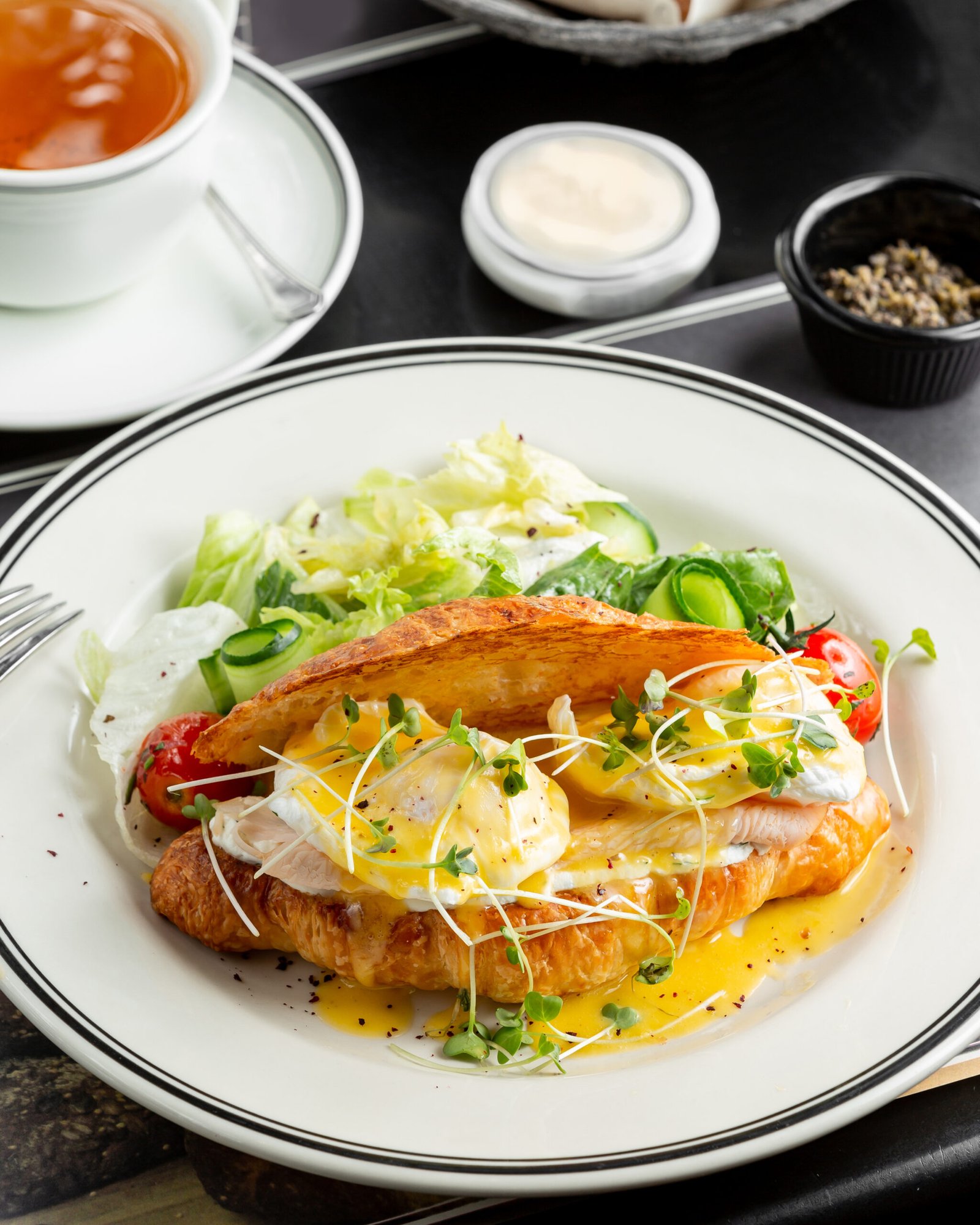 croissant benedict salmon with poched egg hollandaise sauce served with fresh salad scaled